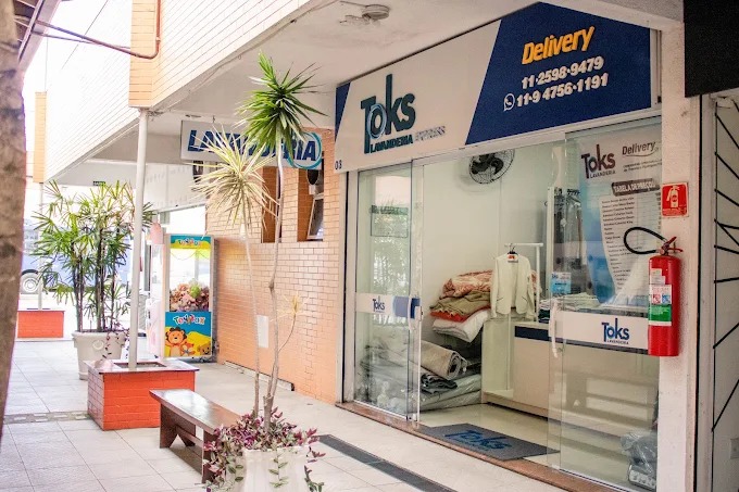 Fachada da Toks Lavanderia Express, com a placa azul da loja e a vitrine de vidro