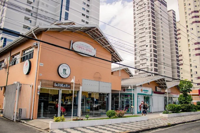Fachada do Condomínio Open Mall, prédio laranja com as lojas ao nível da rua